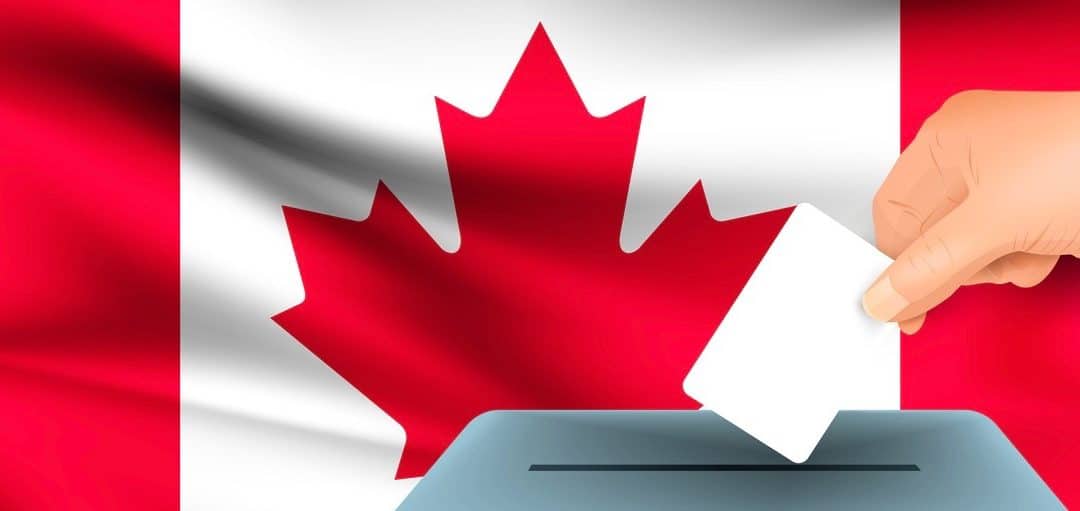 Male hand puts down a white sheet of paper with a mark as a symbol of a ballot paper against the background of the Canada flag.